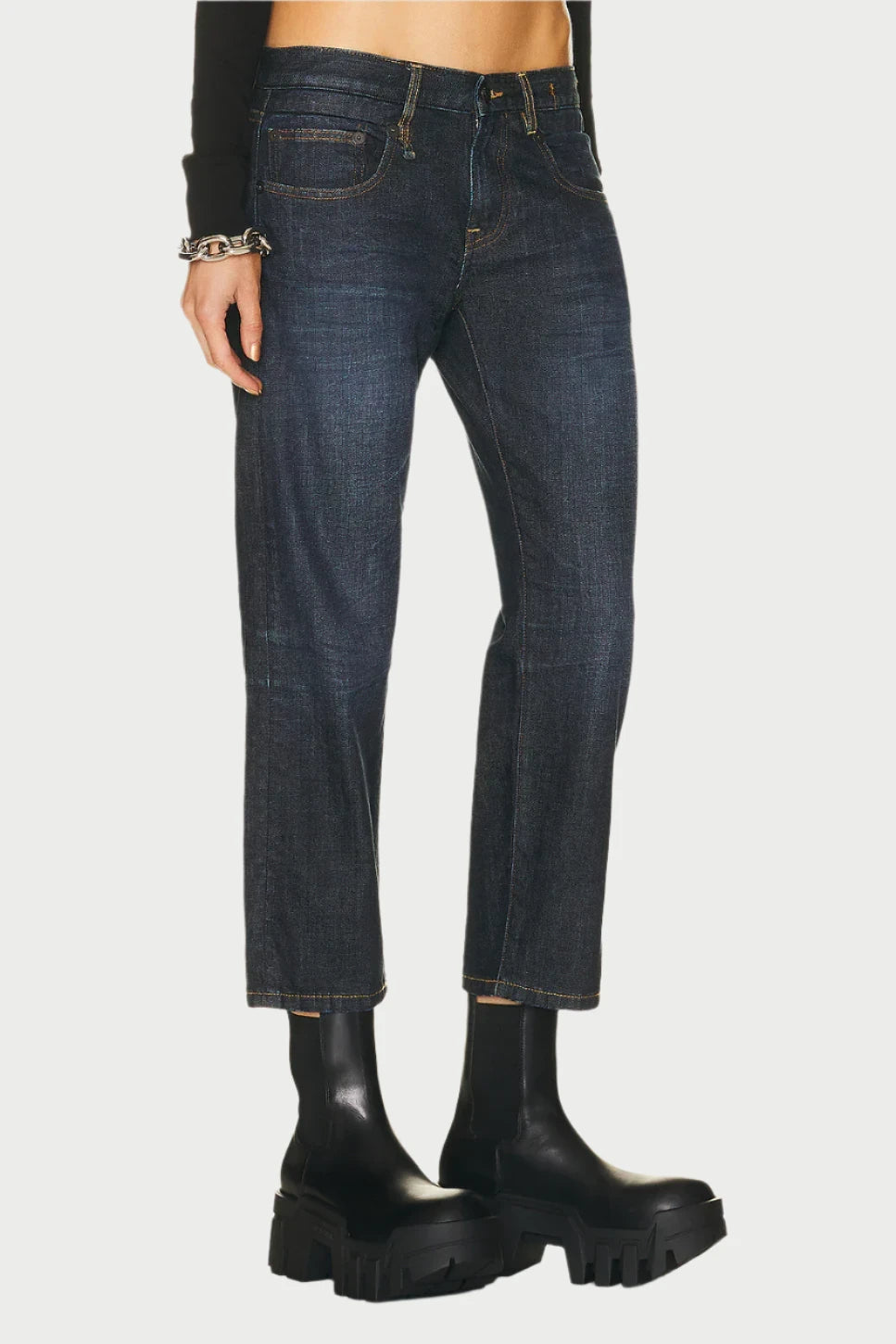 A person wearing dark blue R13 Boy Straight jeans, crafted from Avery Indigo stretch and rigid denim, along with black chunky boots. These jeans feature a classic five-pocket design and a slightly faded finish. The person's upper body and face are out of the frame.