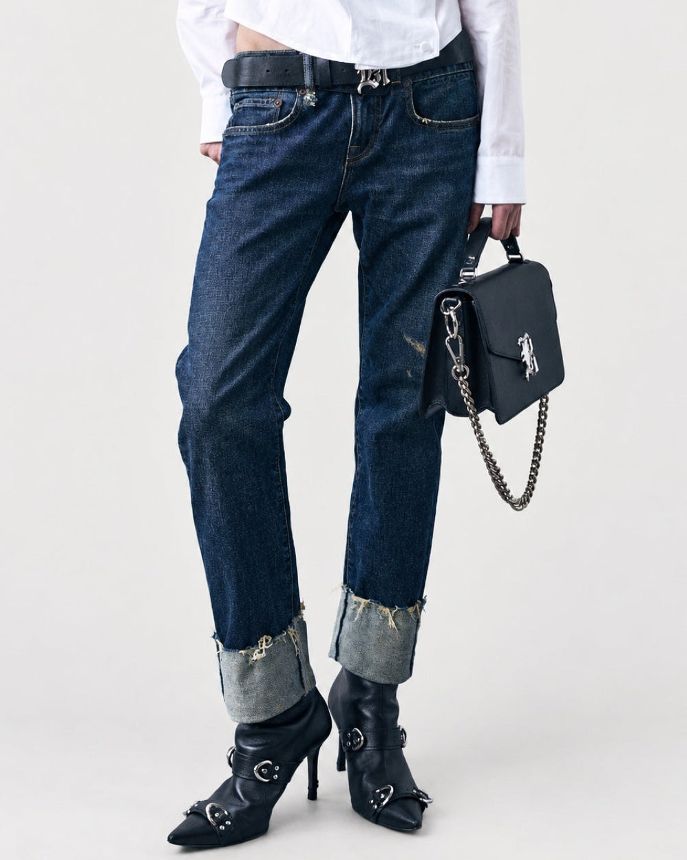 R13 Cuffed Boy Straight jeans in dark blue with wide frayed cuffs, styled with black leather heeled booties and a black chain-strap handbag.