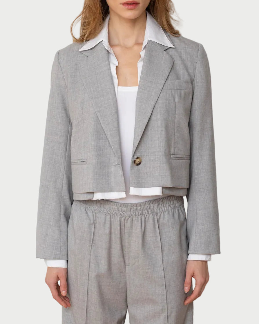 Woman wearing a gray suit with a white shirt against a plain background