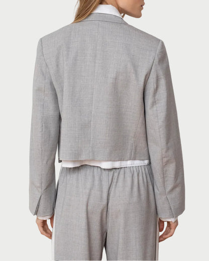 Woman wearing a gray checkered suit with a white shirt on a plain background