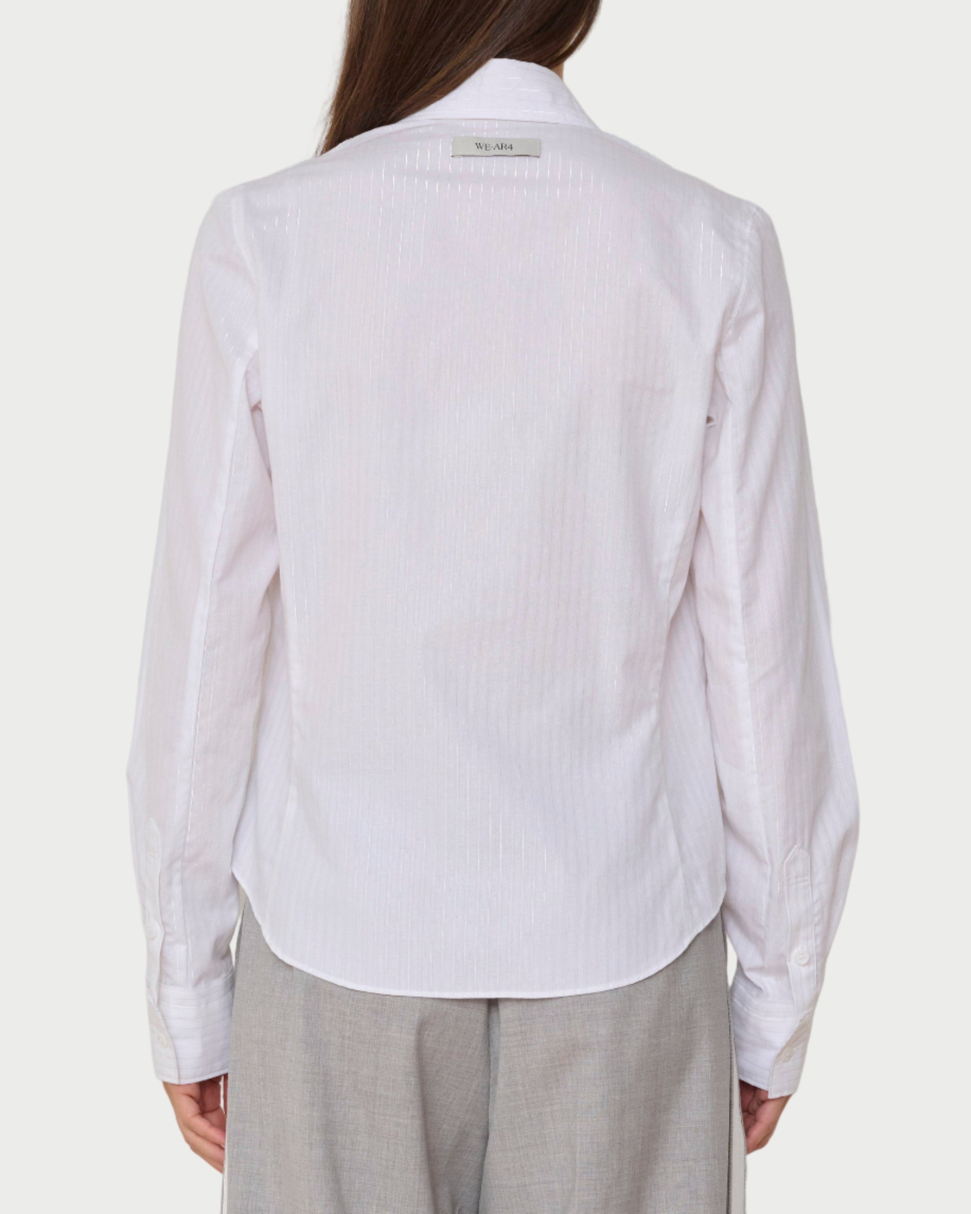 Person wearing a white shirt and light gray pants against a plain background