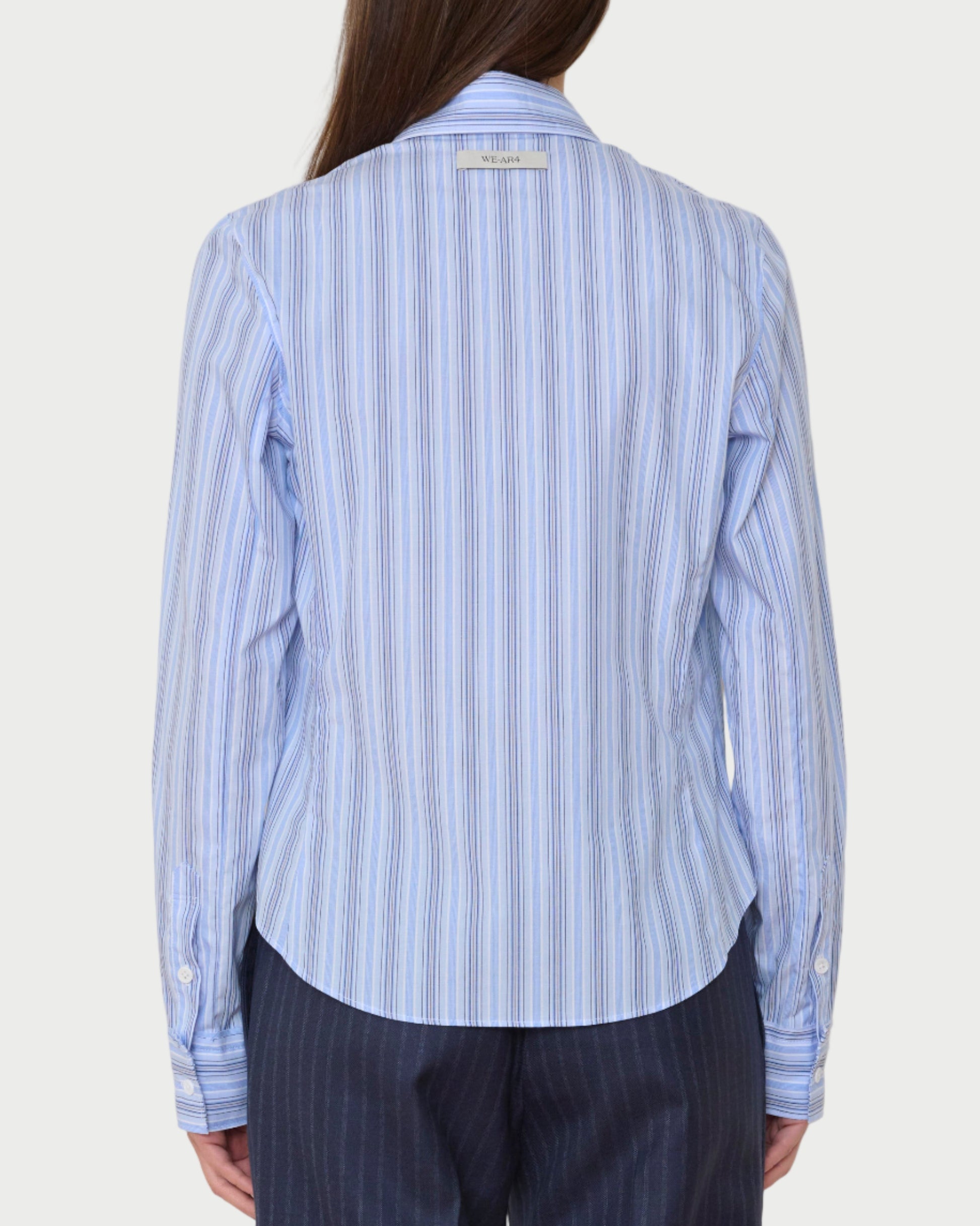 Person wearing a blue striped shirt and dark pants against a white background