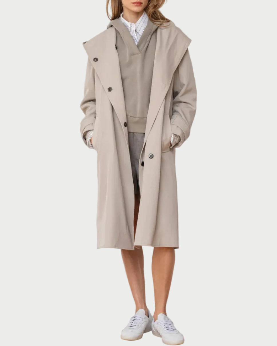 Woman wearing a beige trench coat over a neutral outfit against a white background