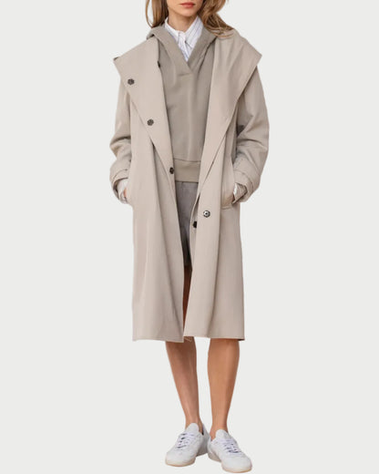 Woman wearing a beige trench coat over a neutral outfit against a white background