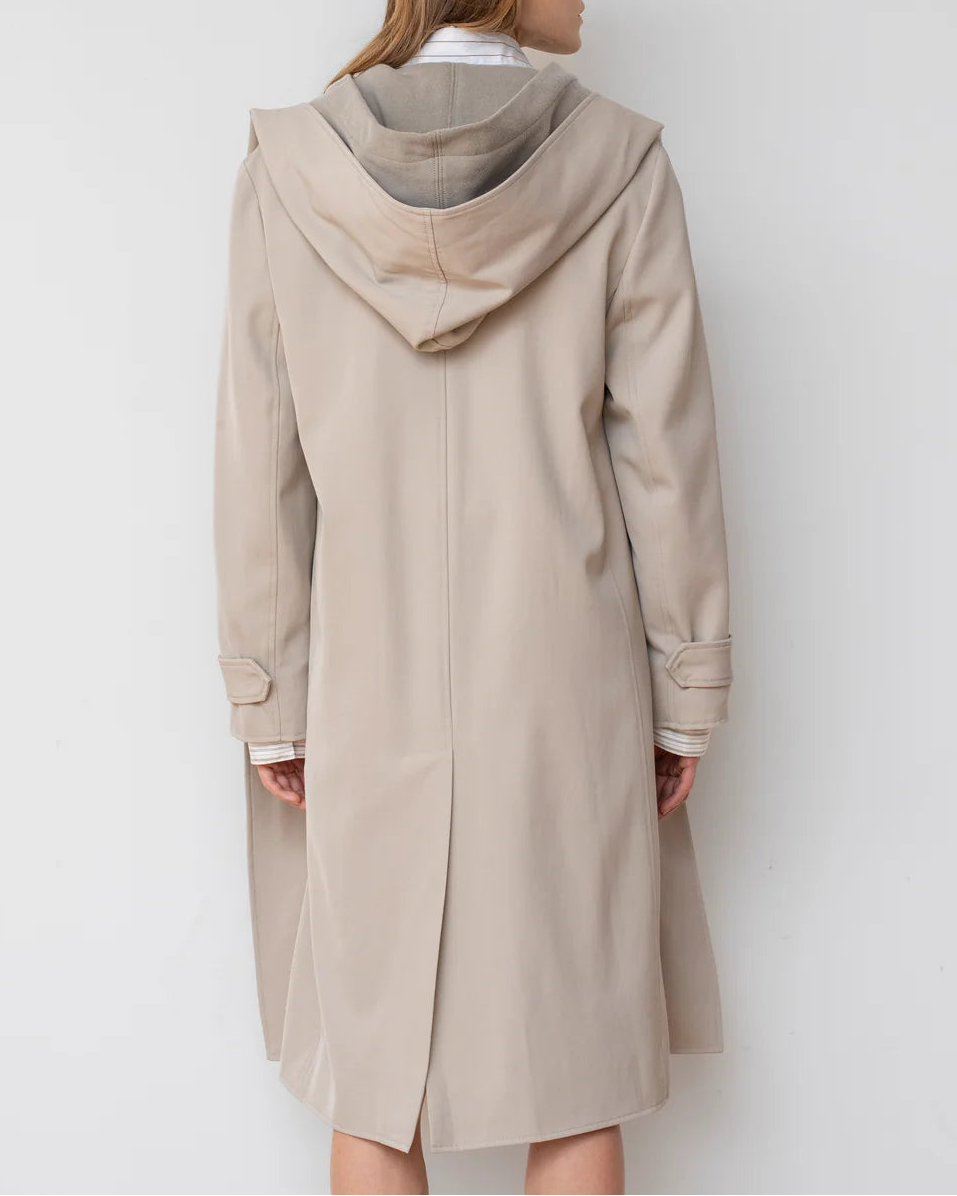 Woman wearing a beige trench coat against a white background