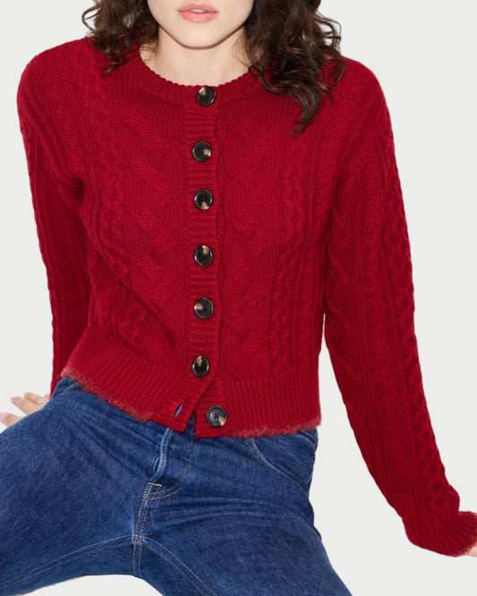 Woman wearing a red cable knit cardigan and blue jeans on a white background