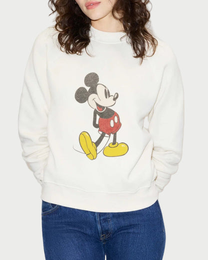 A person wears the RE/DONE Classic Crewneck Mickey Mouse sweatshirt, featuring a vintage-inspired Mickey graphic on the front, paired with blue jeans. The comfy French terry design is by RE/DONE, and the person's face is partially out of frame.