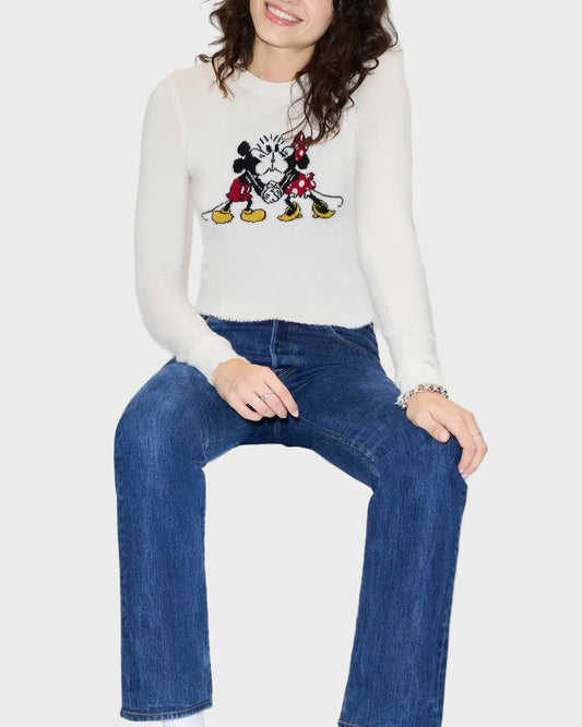 Person wearing a white sweater with a graphic design and blue jeans on a white background