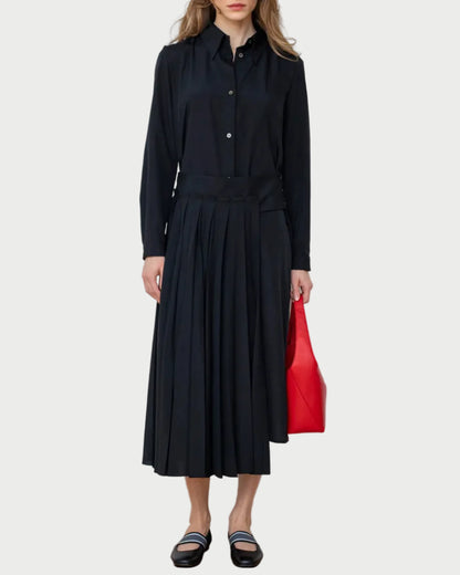 Woman wearing a black outfit holding a red bag against a white wall