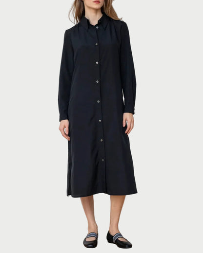 Woman wearing a black dress against a white wall