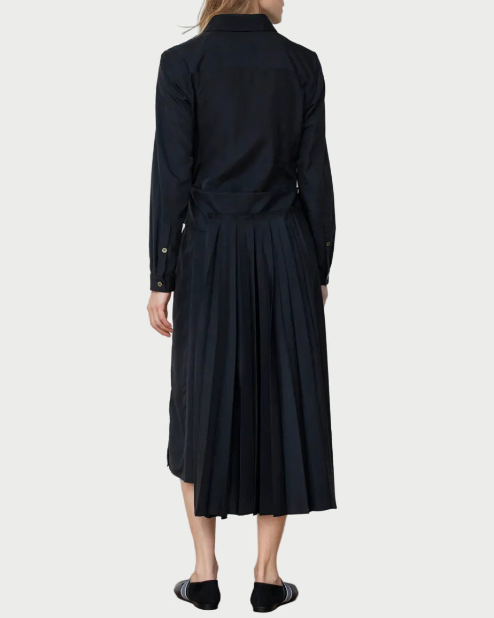 Woman wearing a black dress against a white wall