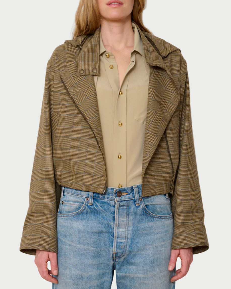 Woman wearing a brown checkered jacket over a beige shirt with blue jeans on a white background