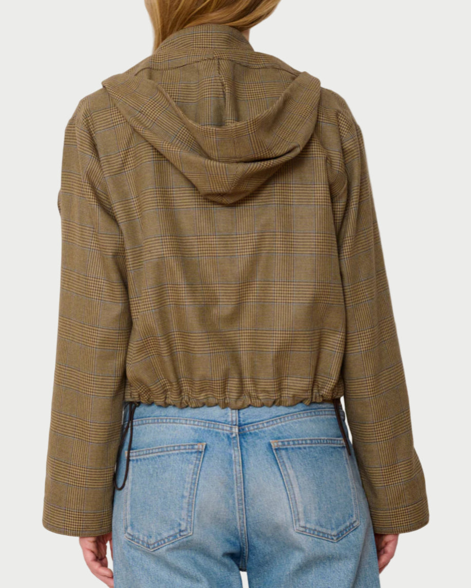 Person wearing a brown plaid jacket and blue jeans against a white background