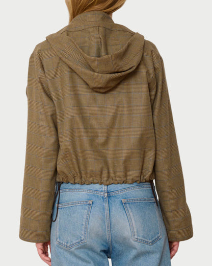 Person wearing a brown plaid jacket and blue jeans against a white background