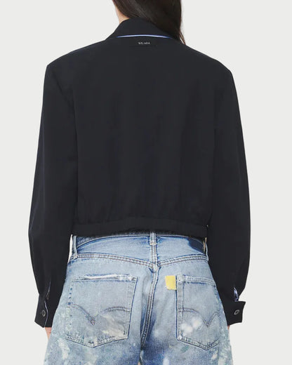 Person wearing a black jacket and light blue denim shorts on a white background