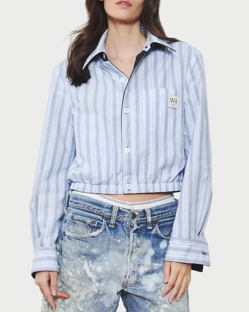 Woman wearing a striped shirt and acid-wash denim shorts on a white background