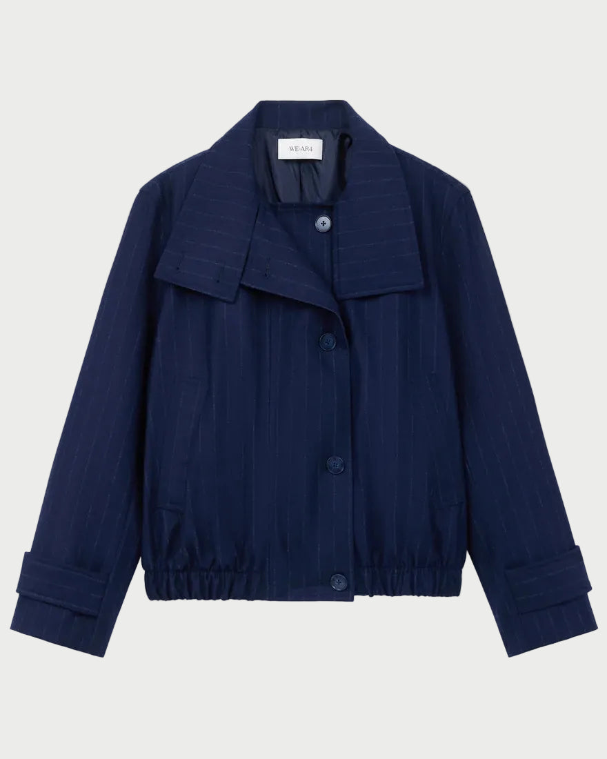 The WE-AR4 Kent Jacket by WE-AR4 is an upcycled wool, navy blue button-up with a collar, cuffed sleeves, subtle pinstripes, and elastic at the hem, shown on a plain light background.