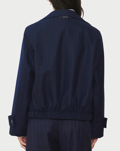 A person wearing the WE-AR4 Kent Jacket by WE-AR4 in navy blue pinstripes, paired with matching pants, shown from the back. This limited edition jacket features an elastic waistband and buttoned cuffs.