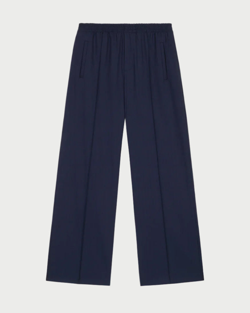 The Prep Trouser by WE-AR4, made from upcycled Italian wool blend in dark navy, features a wide-leg design with an elastic waist. With its two vertical side pockets and relaxed fit, it offers a sleek, minimalist appeal that embodies WE-AR4's forward-thinking ethos.