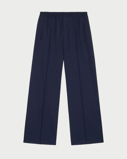 The Prep Trouser by WE-AR4, made from upcycled Italian wool blend in dark navy, features a wide-leg design with an elastic waist. With its two vertical side pockets and relaxed fit, it offers a sleek, minimalist appeal that embodies WE-AR4's forward-thinking ethos.