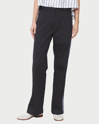 Person wearing navy pants with a white stripe on a wooden floor and white wall background