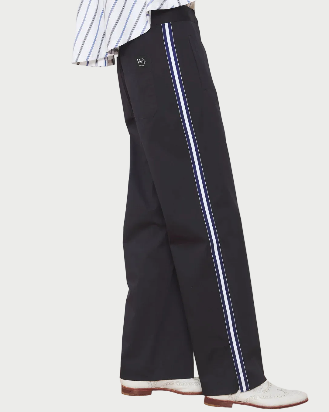 Black pants with white stripes worn by a person on a wooden floor.