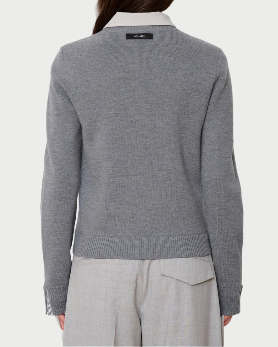 Person wearing a gray sweater with a visible brand logo on a white background