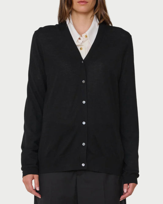 Woman wearing a black cardigan over a white shirt on a plain background