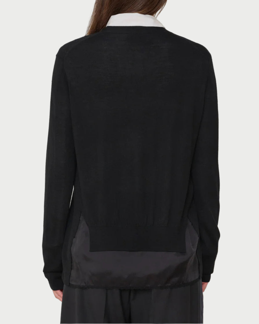 Person wearing a black sweater and pants against a white background