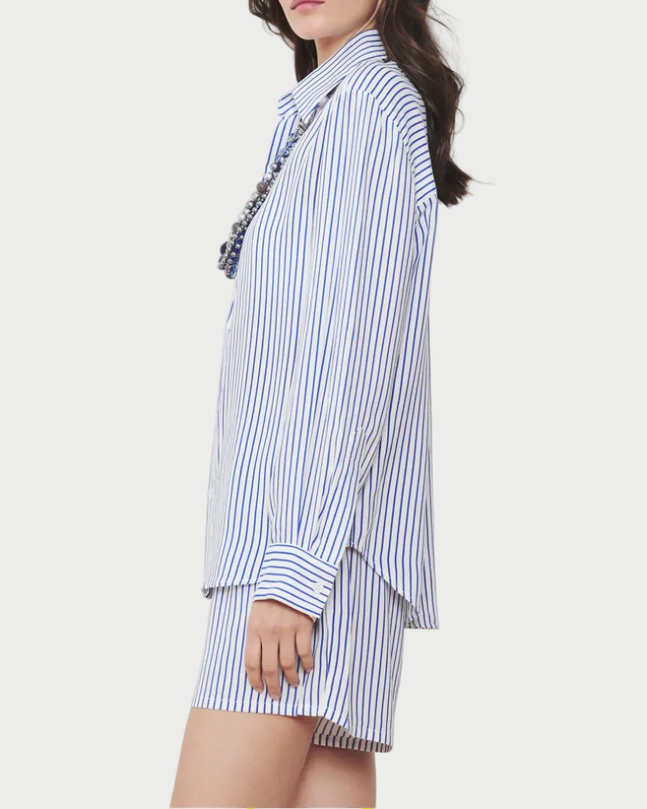 Woman wearing a blue and white striped shirt and shorts against a plain background