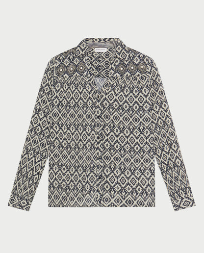 The Maison Hotel Ruby Tuesday Ikat Top is a long-sleeved, button-up shirt with a black and white diamond pattern, pointed collar, and decorative details on the chest and shoulders.