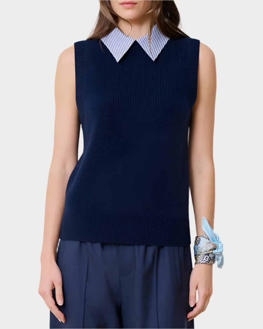 Against a plain backdrop, an individual dons the School Vest Navy by WE-AR4, a sleeveless sweater made from upcycled merino wool. A white-and-blue striped collared shirt complements their long brown hair and light blue scarf on the wrist—an epitome of sustainable fashion.
