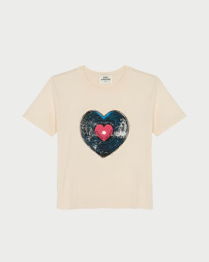 The Record Everyday Tee by Sunny Somewhere is a beige short-sleeve top featuring a large sequin heart inspired by a heart-shaped record, with a blue outer heart and pink center on the front.