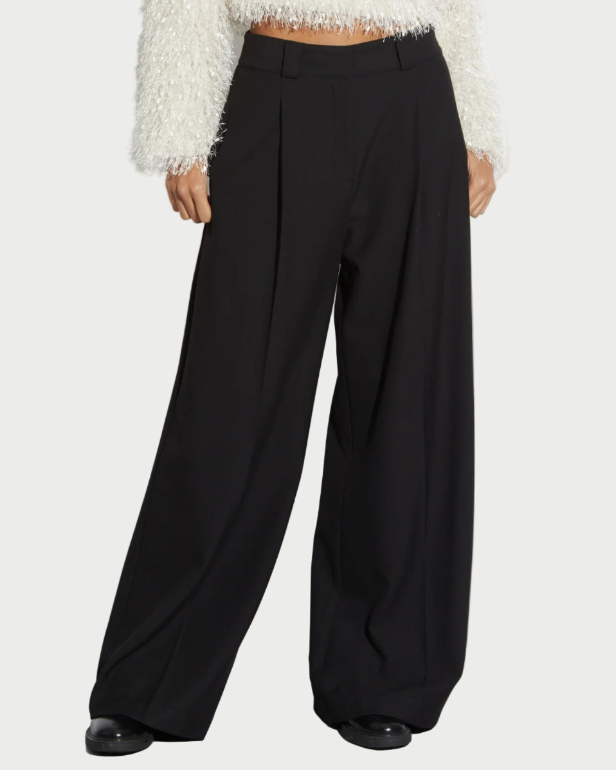 Wearing Saint Art NY Tiffany Wide Leg Pants, a person stands against a plain background in wrinkle-resistant, high-waisted trousers. Only the lower half of the body is visible.