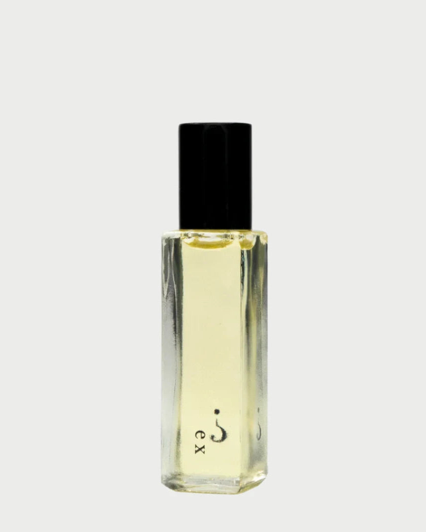 Clear glass perfume bottle with a black cap, featuring a yellow liquid that exudes a floral allure. The elegant "Ex" design on the front invites you to discover the sophisticated essence of sandalwood within Riddle Oil's 8ml fragrance.