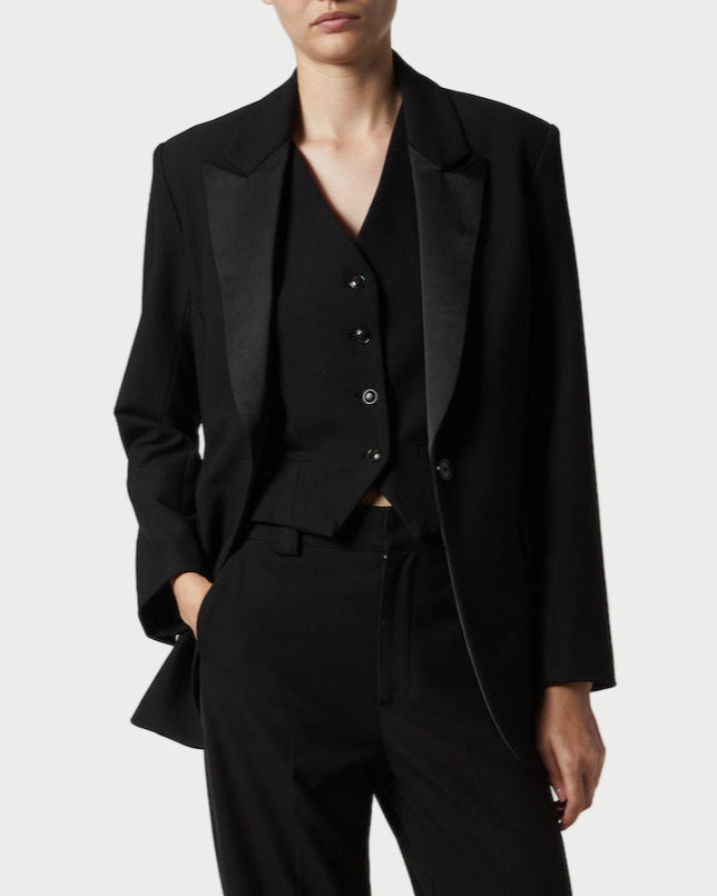 Person wearing a black suit on a plain background