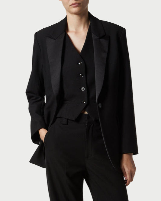 Person wearing a black suit on a plain background