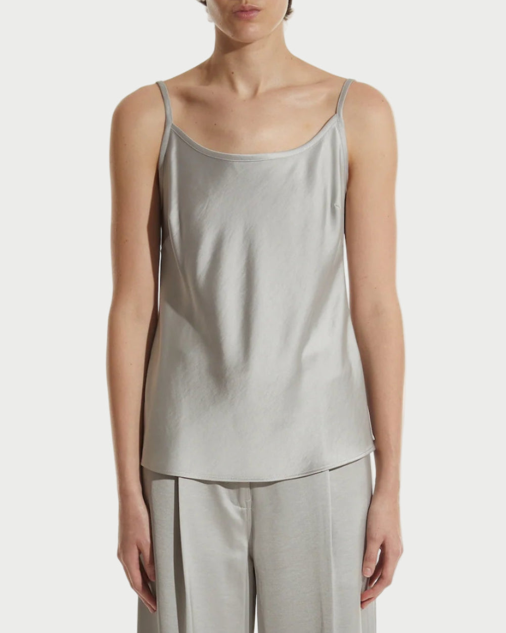 Person wearing a light gray sleeveless top and wide-leg pants on a white background