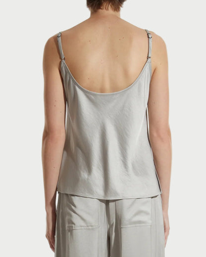 Person wearing a light gray satin pajama set on a white background