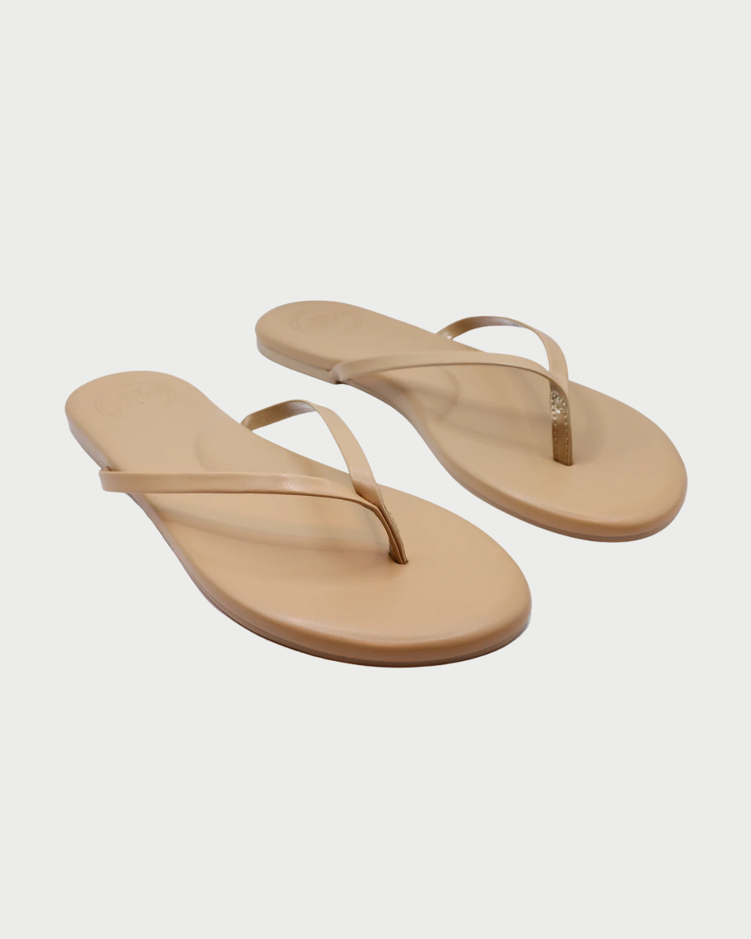 Pair of beige flip-flops on a light gray background