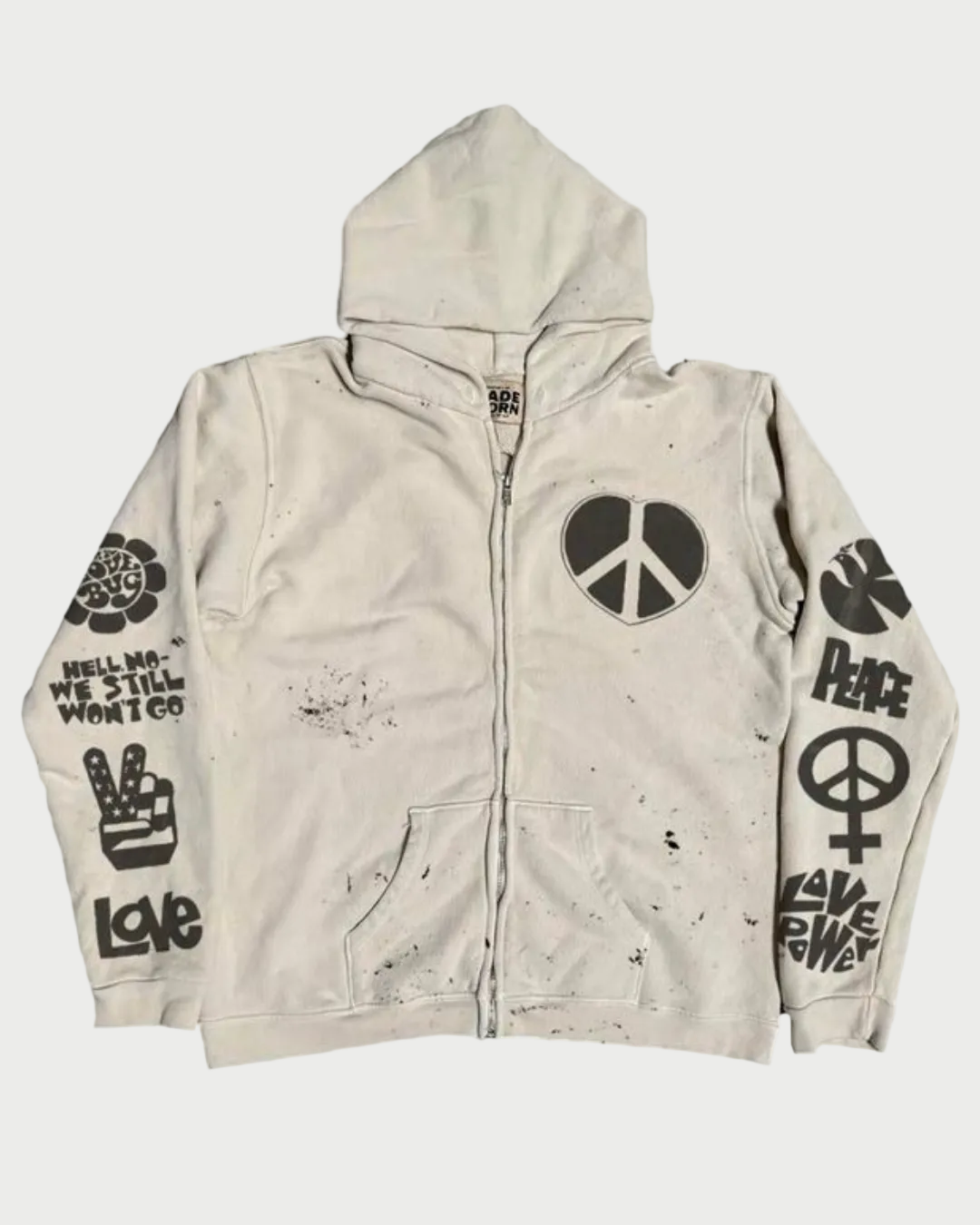 The Madeworn "Love Trip" Zip Up Hoodie by Madeworn is a vintage white zip-up with a hood, black peace symbols, "Peace" and other peace-themed text, psychedelic graphics on front and sleeves, and bold black splatter marks.