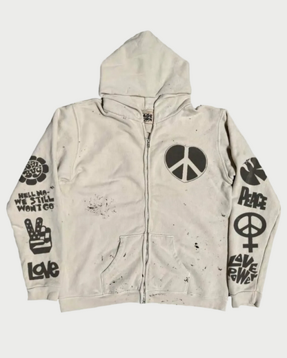 The Madeworn "Love Trip" Zip Up Hoodie by Madeworn is a vintage white zip-up with a hood, black peace symbols, "Peace" and other peace-themed text, psychedelic graphics on front and sleeves, and bold black splatter marks.