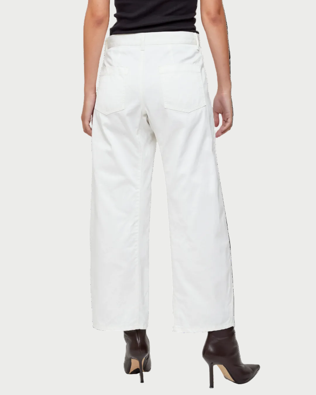 A person is shown from the back in Moussy Gusset Cargo Pant (mid-rise, white, wide-leg) by Moussy, paired with black heeled boots and a sleeveless black top. Their hands are by their sides against a plain white background.