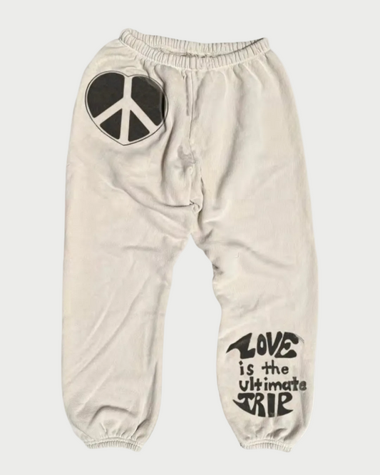 Beige sweatpants with peace symbol and 'Love is the ultimate trip' text on a white background