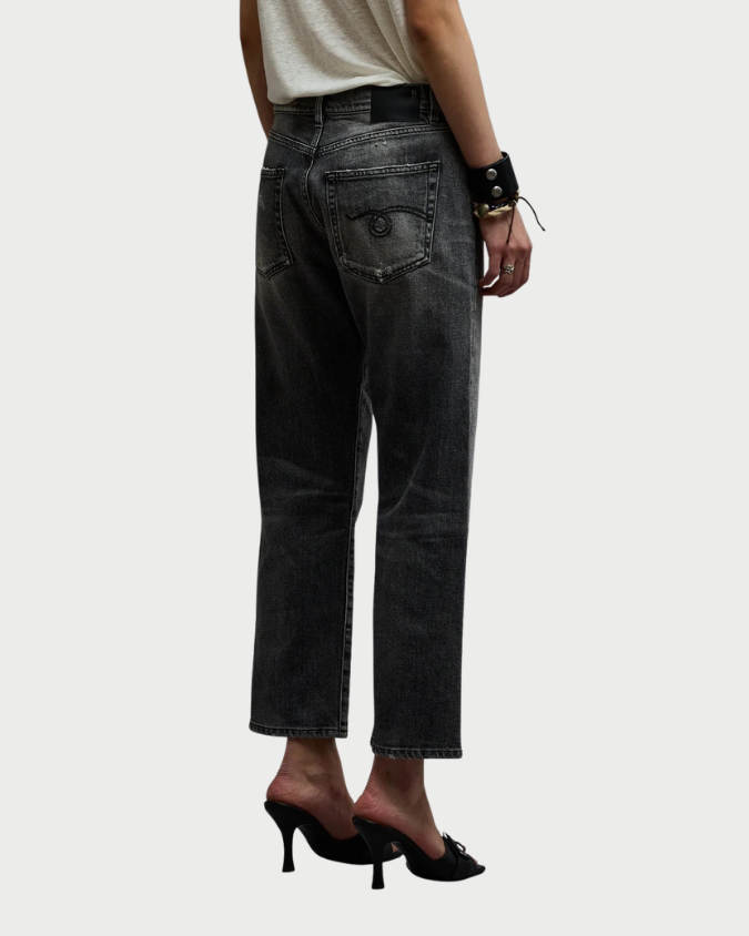 A person wearing R13 Boyfriend Jean Vintage Grey jeans with a faded wash and black heeled mules.