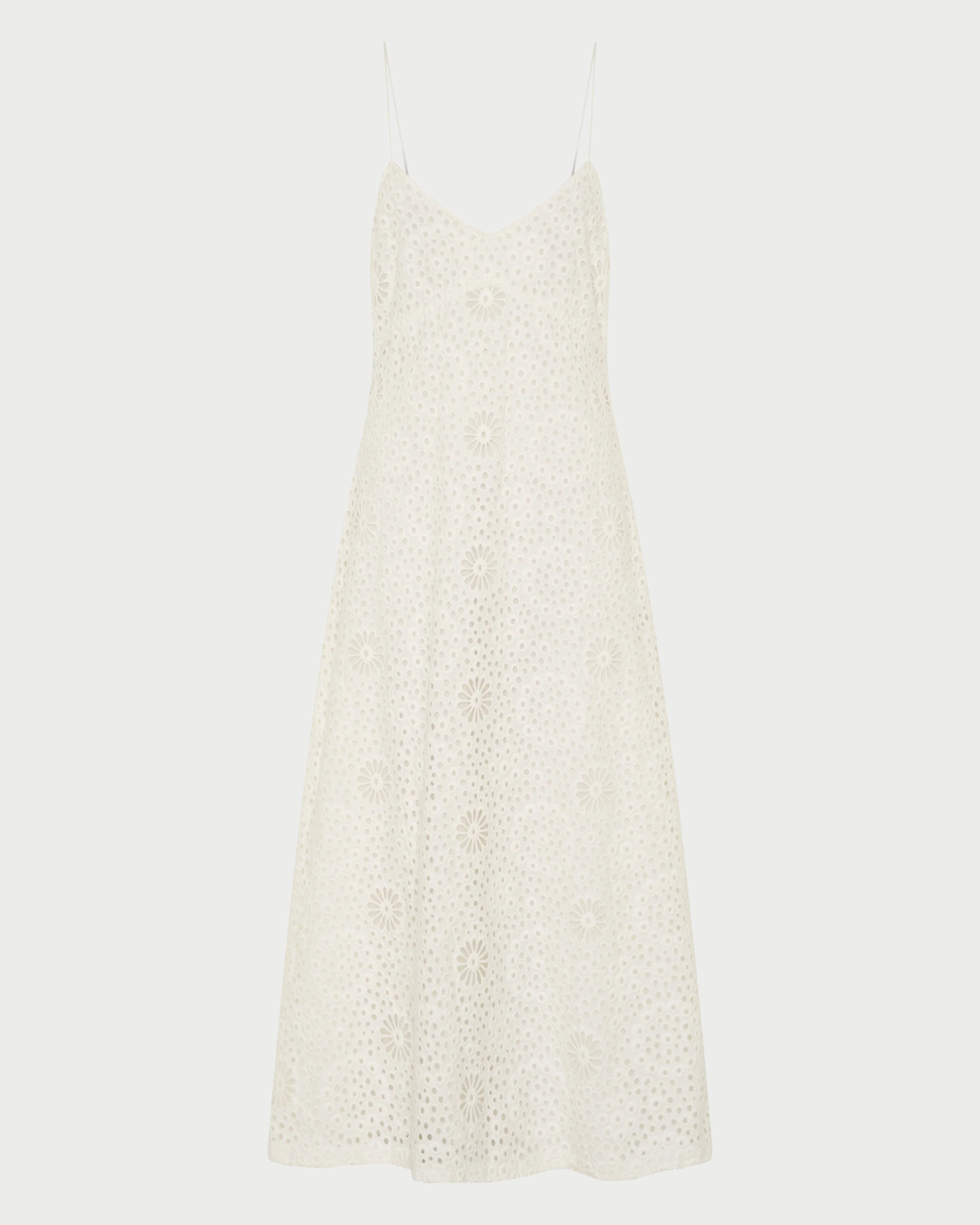 The Ilio Nema Ino Dress by Ilio Nema is a sleeveless white cotton dress with spaghetti straps, an A-line silhouette, and an allover embroidered floral pattern—perfect for summer.