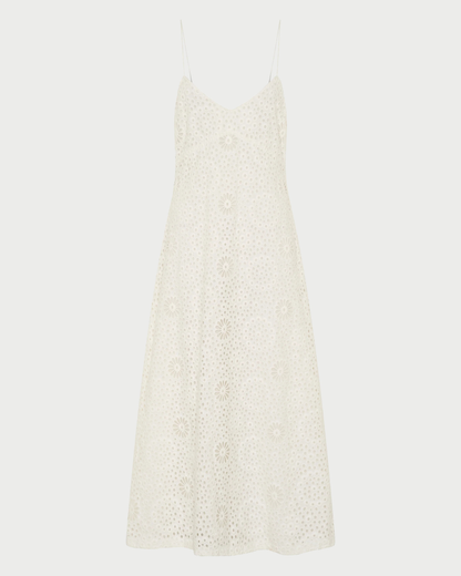 The Ilio Nema Ino Dress by Ilio Nema is a sleeveless white cotton dress with spaghetti straps, an A-line silhouette, and an allover embroidered floral pattern—perfect for summer.
