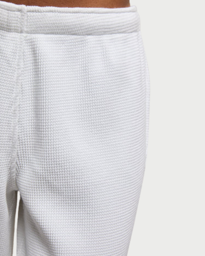 Close-up of textured white pants on a light gray background