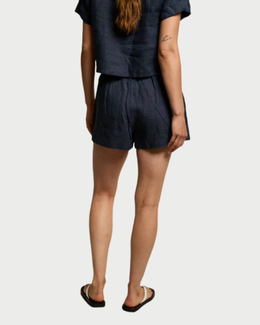 Person wearing a navy blue outfit with shorts on a white background