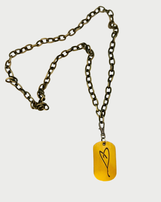 Necklace with a yellow tag featuring a black heart design on a white background